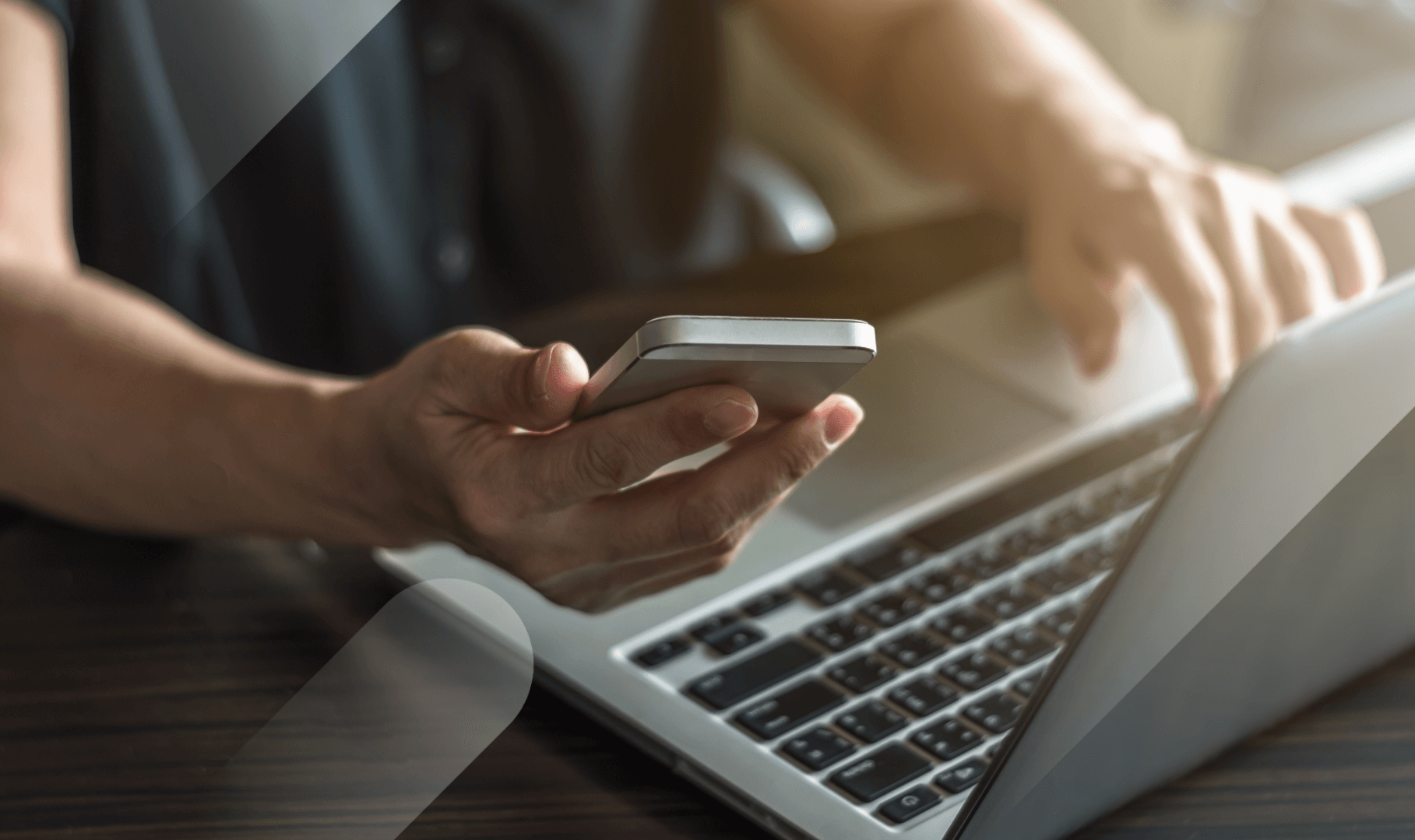 man on phone typing on laptop reping keywords for SEO
